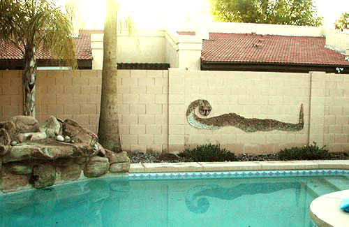 Wall around a pool with a stone mosaic snake